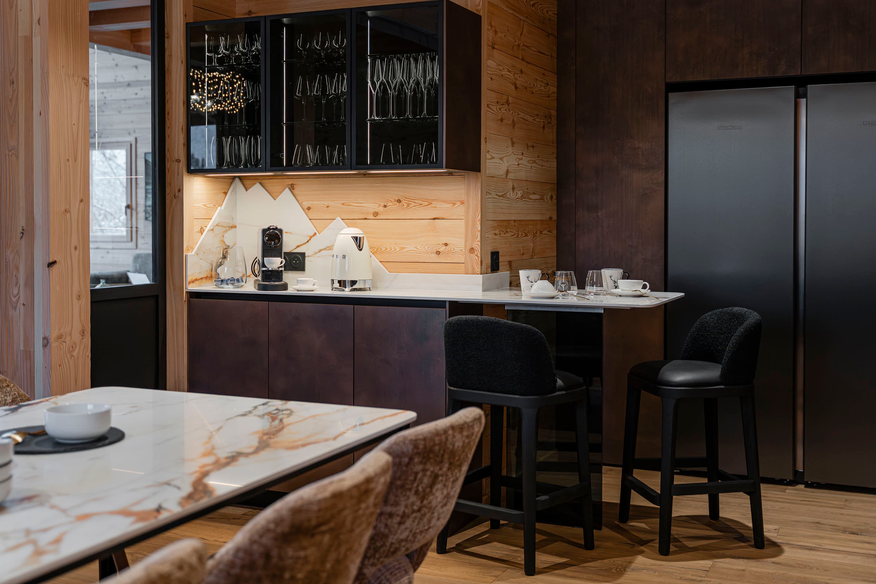 Bar-comptoir avec tabourets, réfrigérateur américain noir et vitrine à verres rétroéclairée