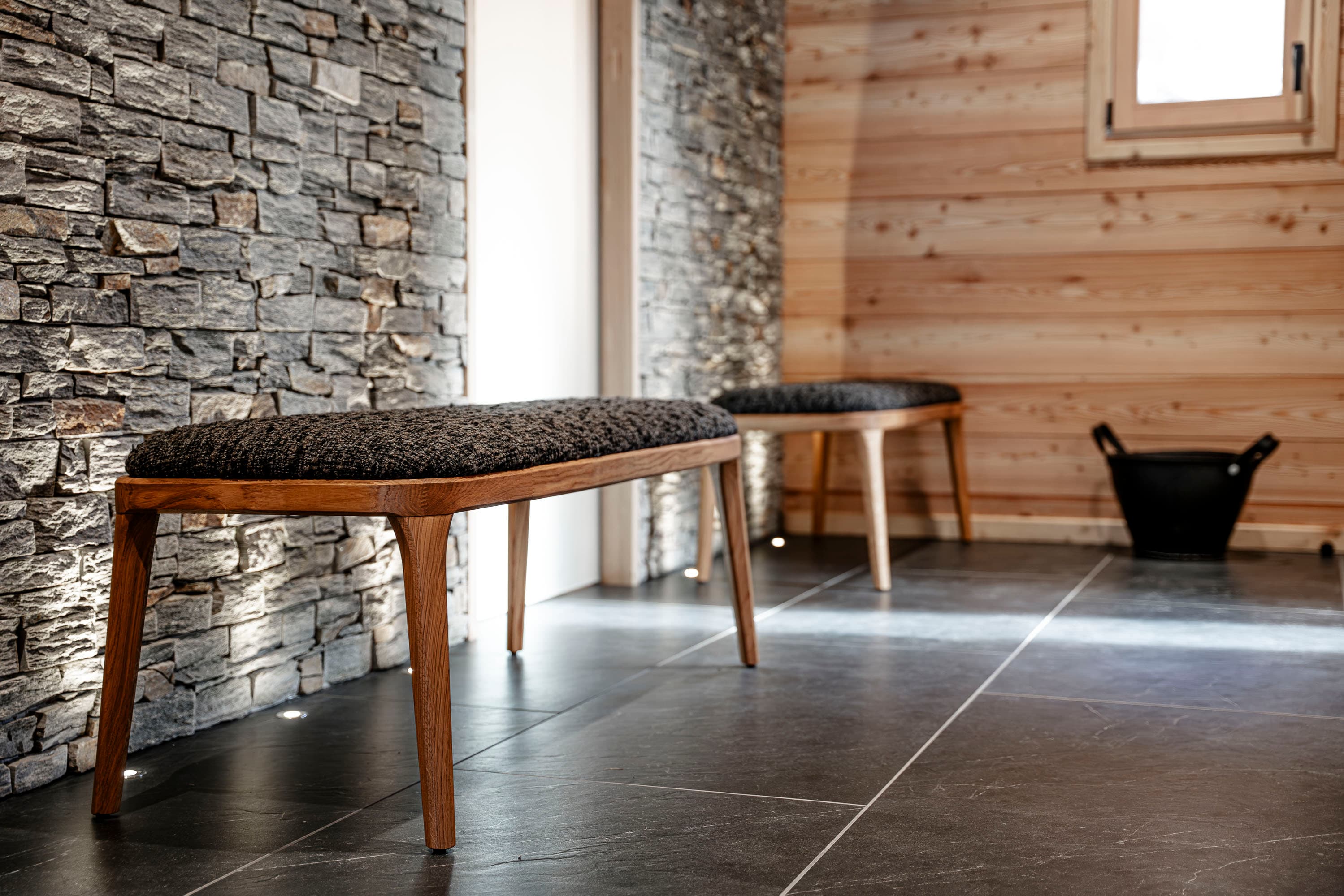 Banc rembourré devant le mur en pierre naturelle du hall d'entrée