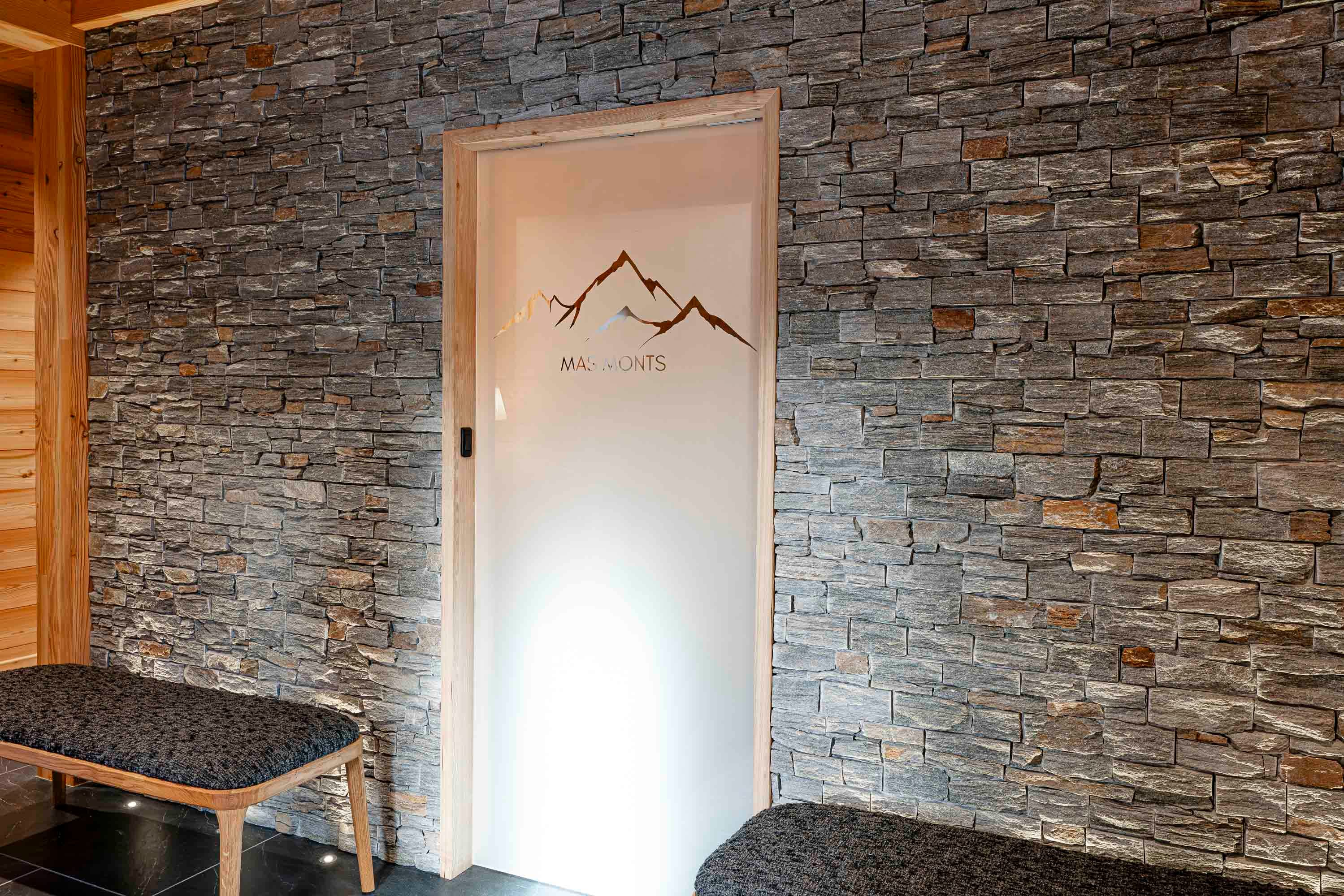 Porte intérieure vitrée avec logo Mas Monts gravé sur fond de mur en pierre