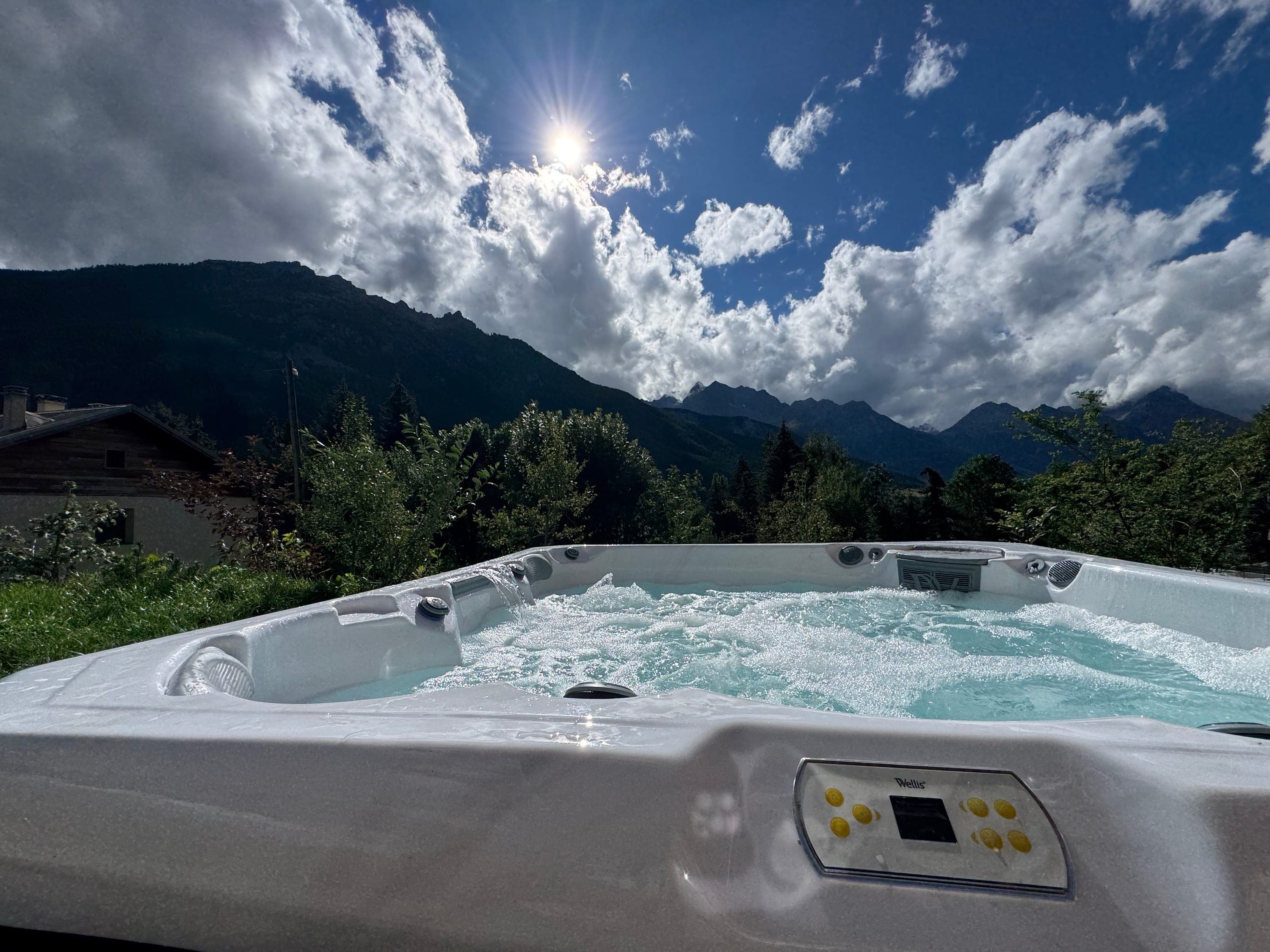 Jacuzzi extérieur chauffé en marche, eau bouillonnante face aux montagnes sous le soleil