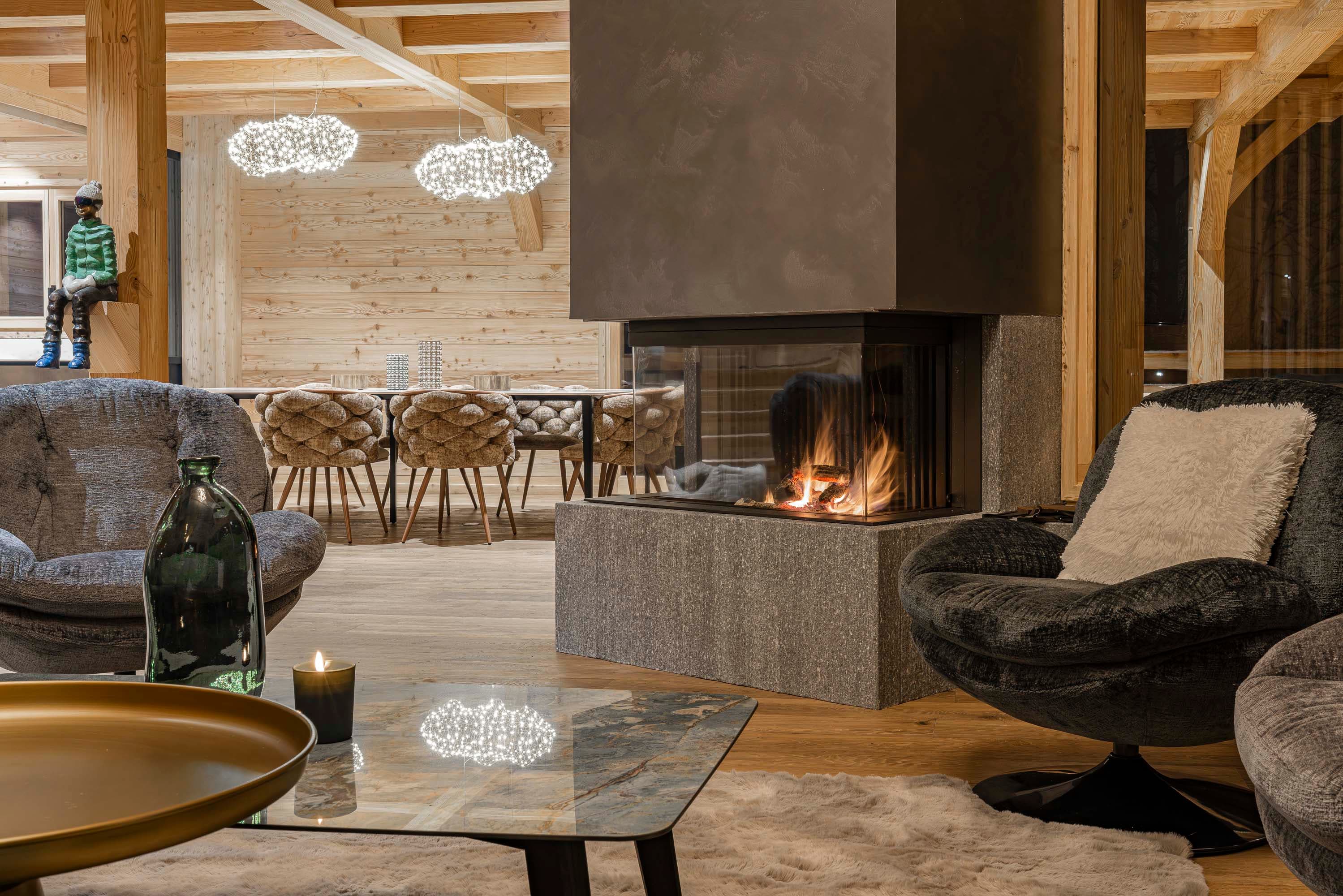 Salon avec fauteuils en velours, cheminée suspendue et suspensions nuage dorées