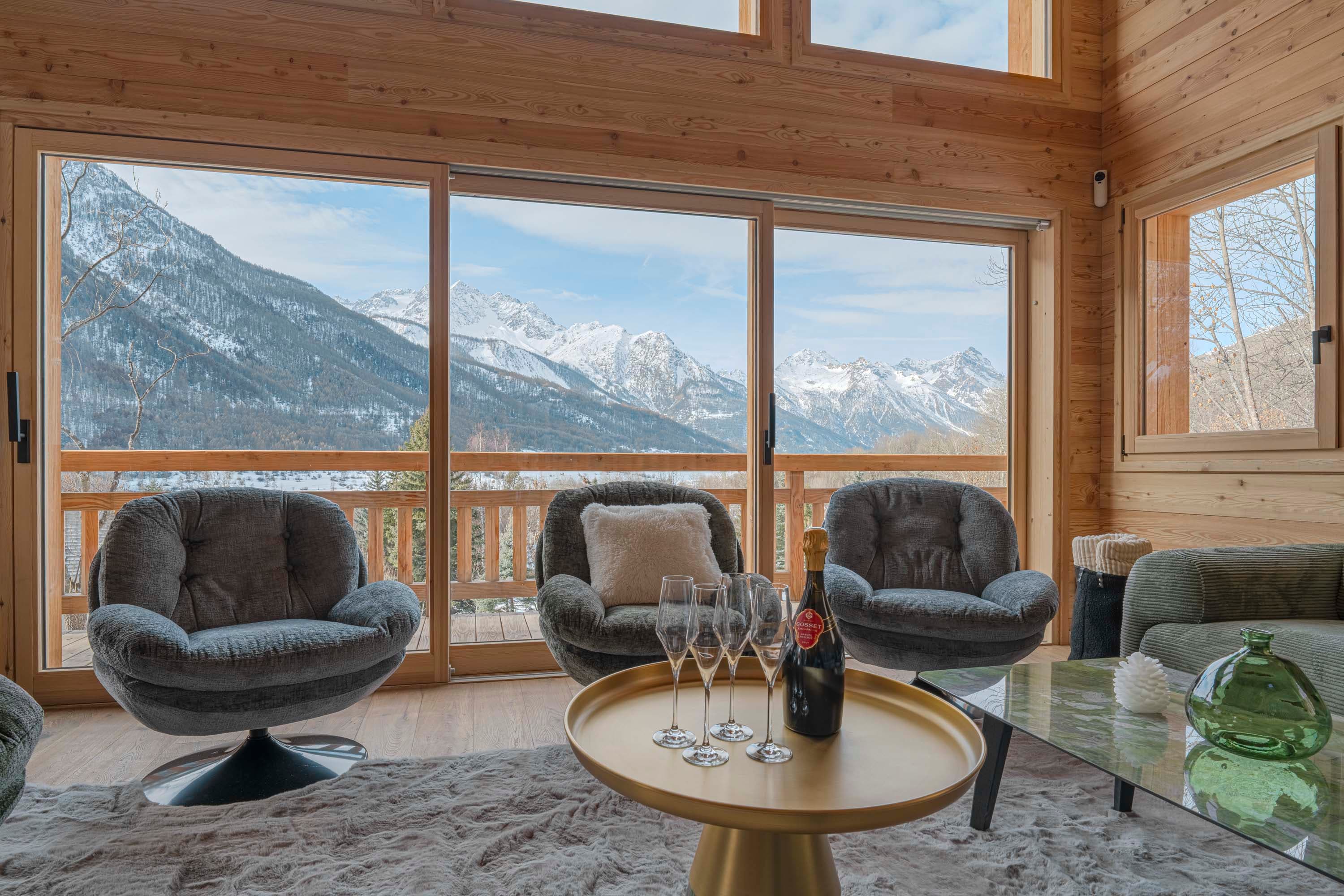 Fauteuils pivotants, champagne et flûtes devant la baie vitrée panoramique