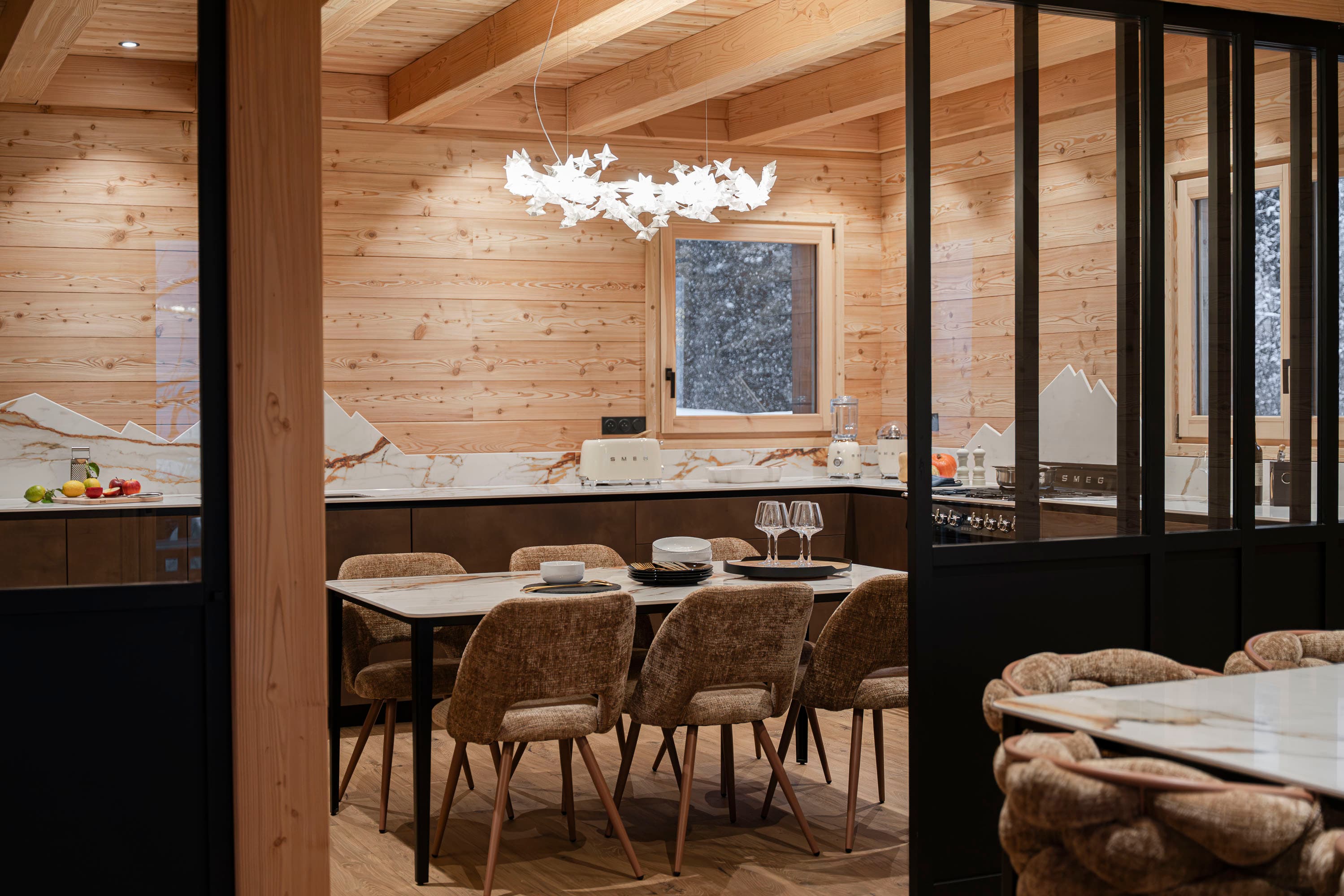 Coin cuisine vu depuis la salle à manger à travers la verrière noire, suspension en papillons blancs