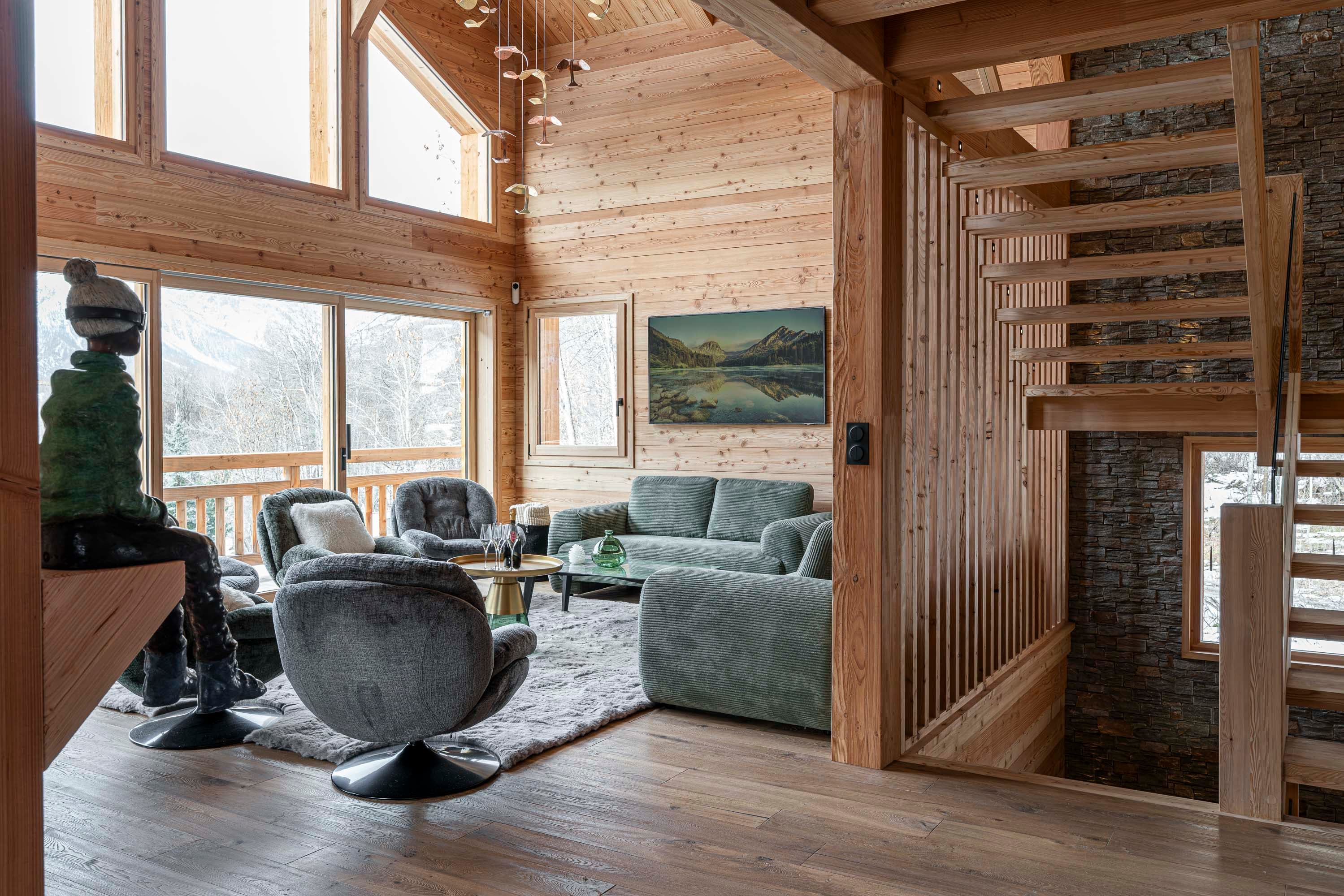 Salon avec sculpture de skieur assis, canapé vert et escalier en pierre