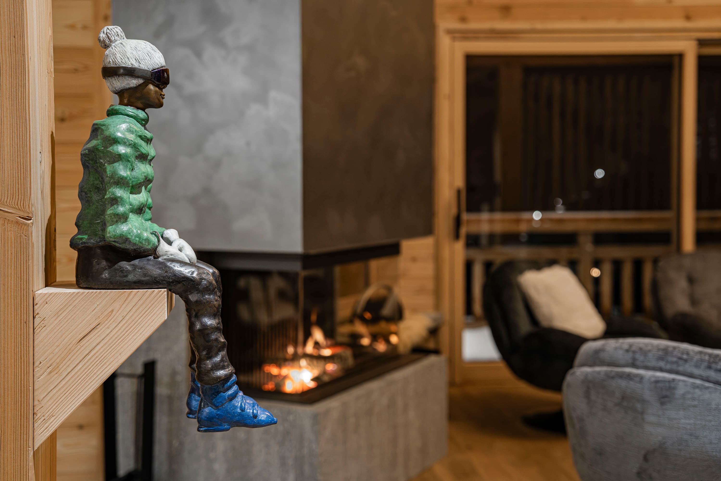 Sculpture de skieur en gros plan devant la cheminée allumée et le salon en arrière-plan