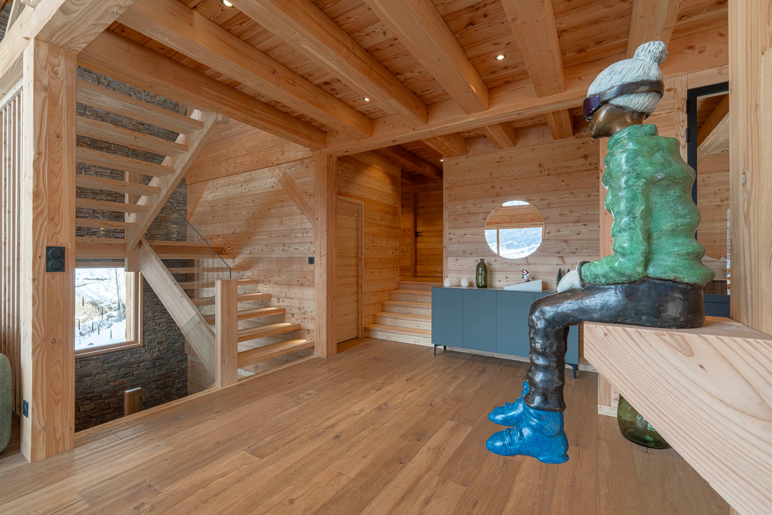 Sculpture de skieur et escalier en bois avec mezzanine, miroir rond et console