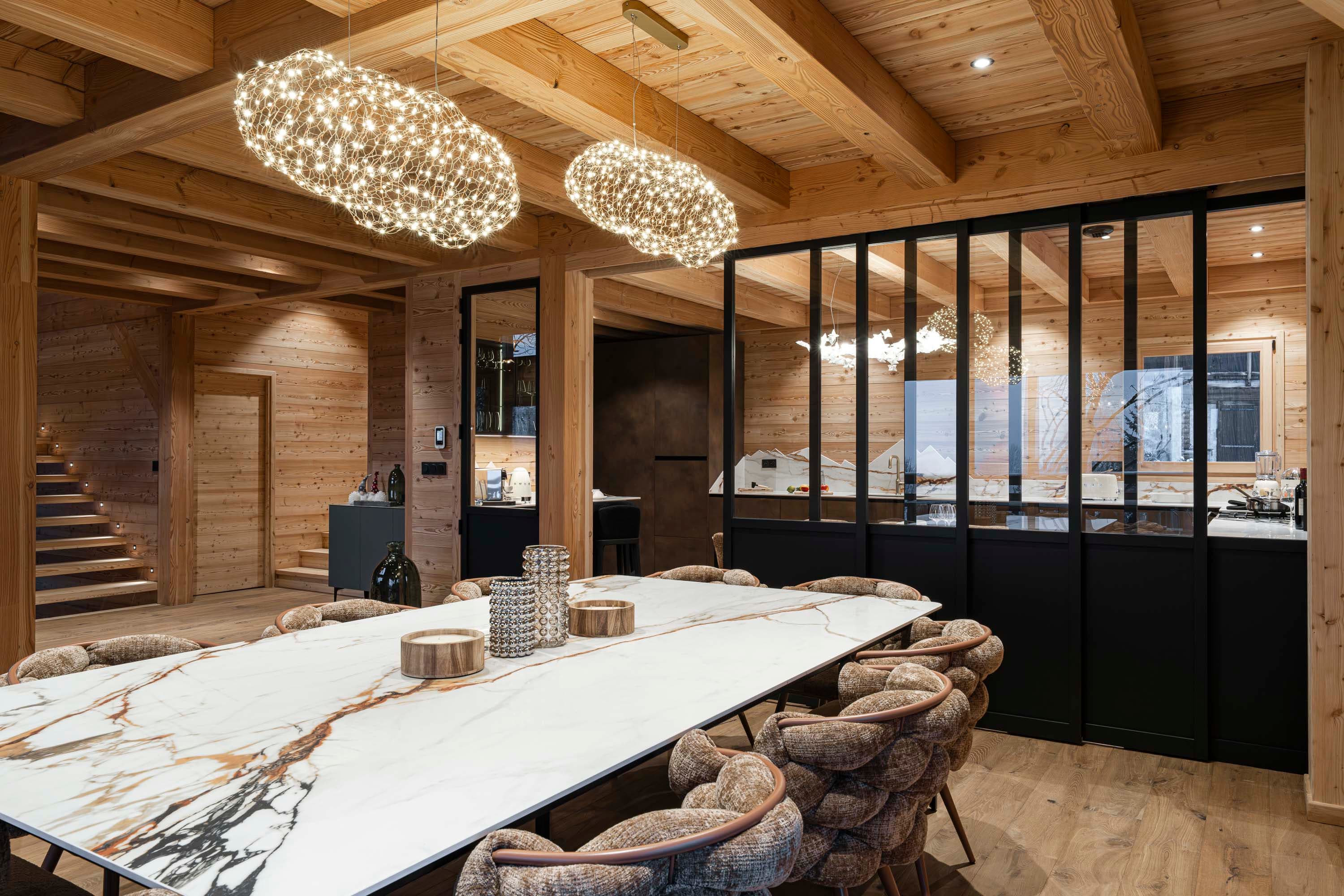 Table en marbre avec verrière noire ouvrant sur la cuisine et suspensions nuage