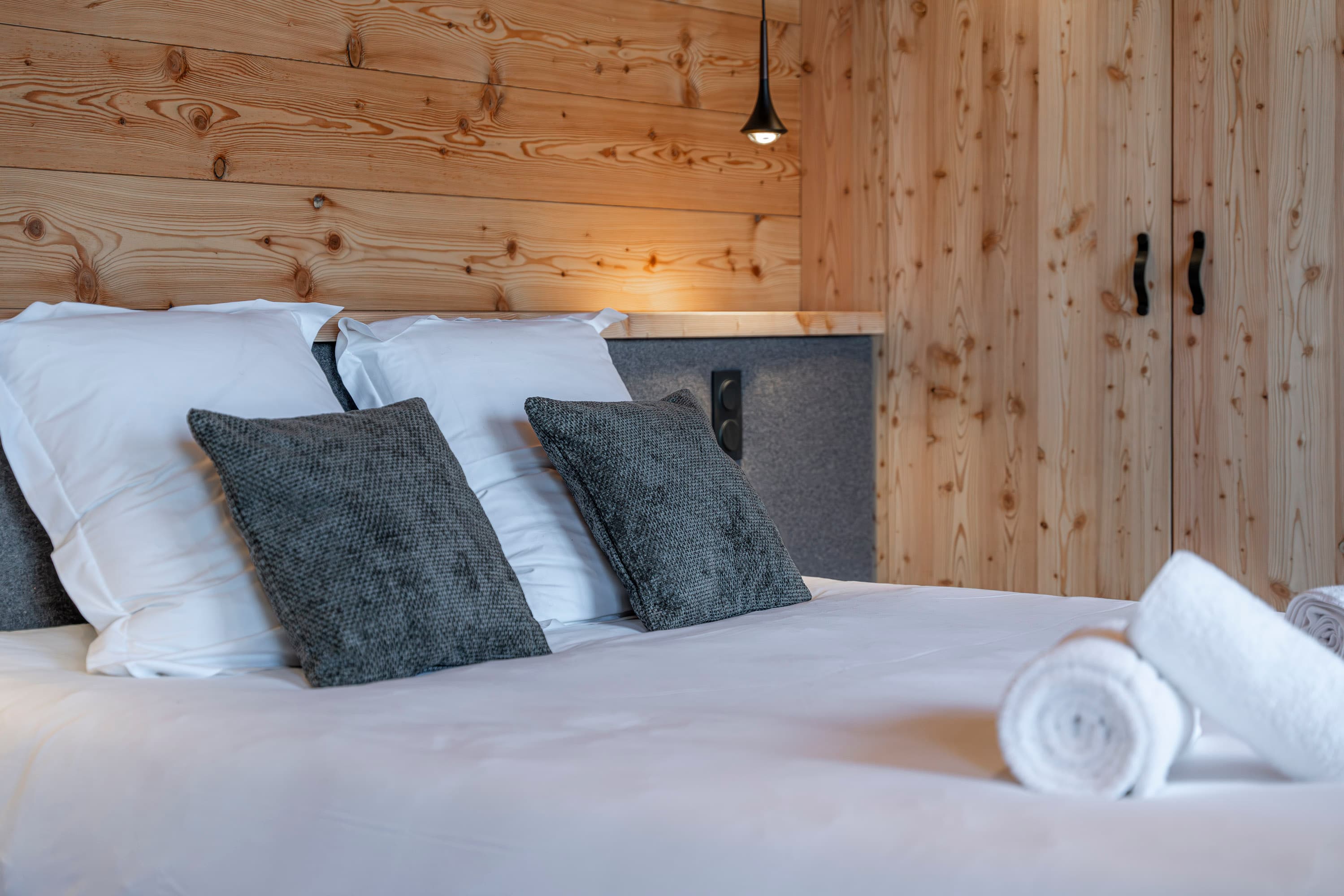 Détail des oreillers et coussins gris sur le lit blanc avec suspensions noires