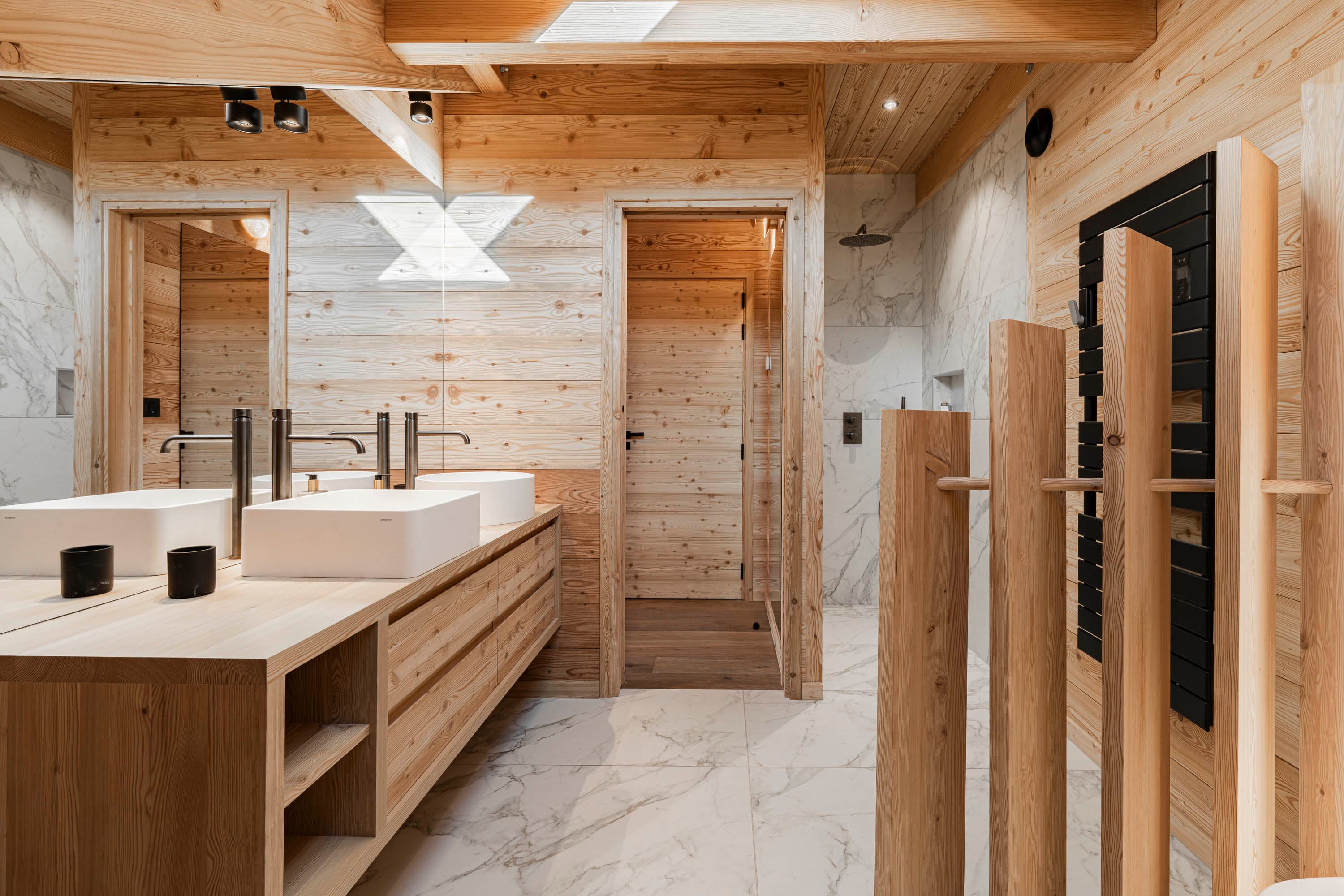 Salle de bain en marbre blanc avec double vasque, douche et sèche-serviettes