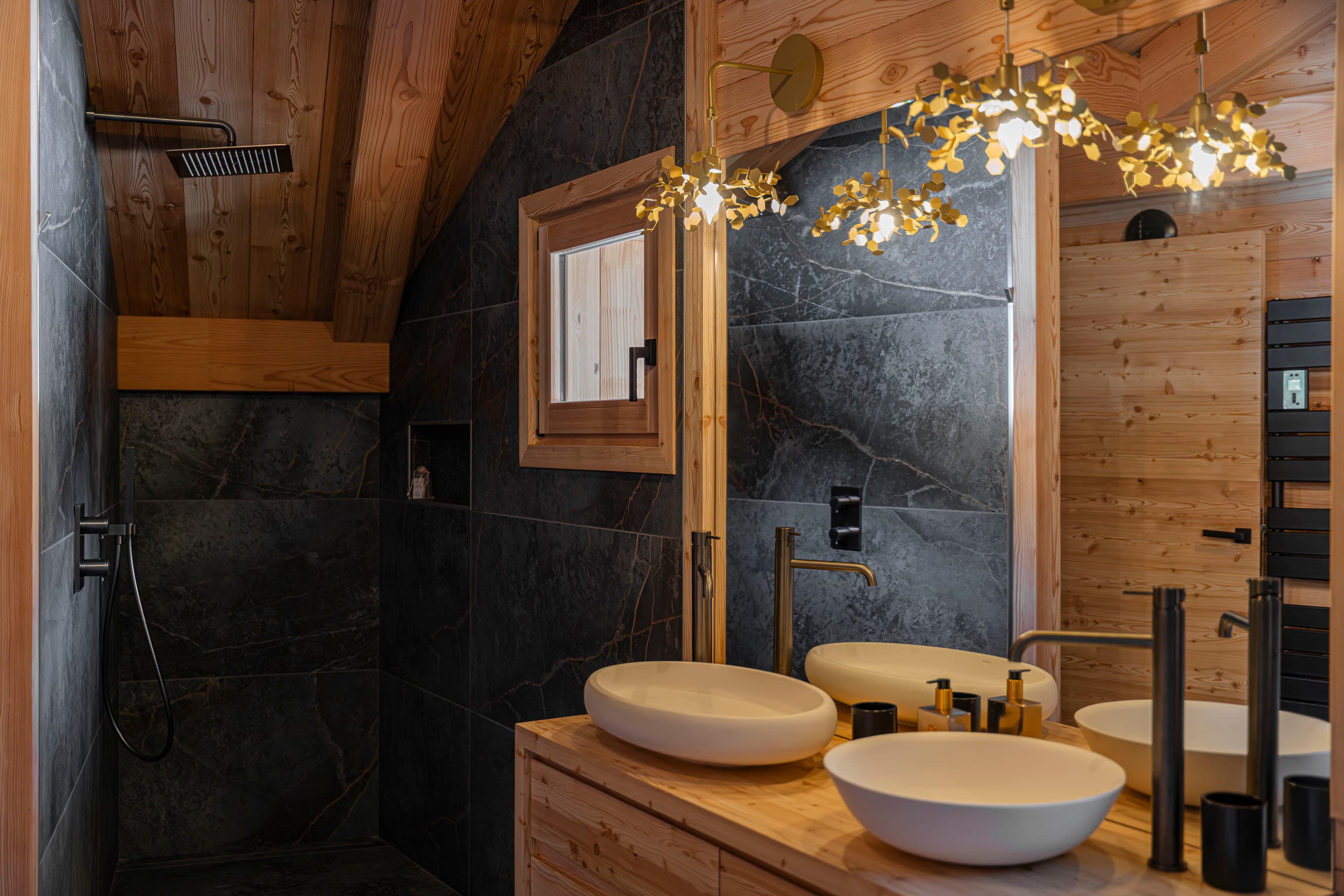 Salle de bain parentale en ardoise noire avec double vasque sur meuble en bois et suspension dorée